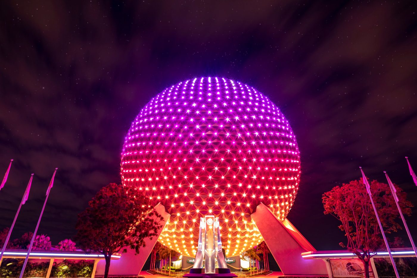 Spaceship Earth at EPCOT lit in pink and gold at night